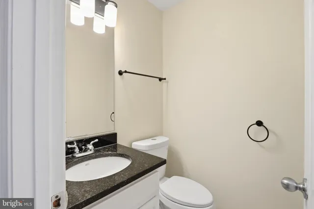 a bathroom with a granite countertop toilet sink and mirror