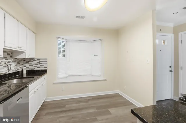 a kitchen with granite countertop white cabinets and sink