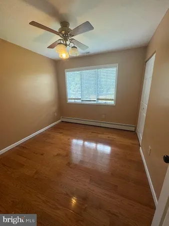 an empty room with wooden floor fan and windows