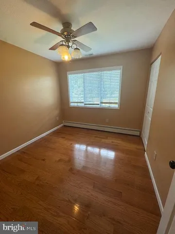 an empty room with wooden floor fan and windows