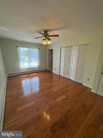 an empty room with wooden floor chandelier fan and windows