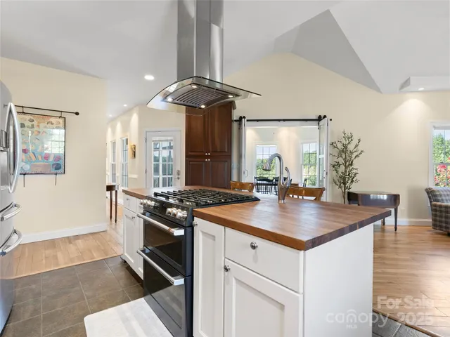 a kitchen with stainless steel appliances granite countertop a stove a refrigerator a sink a dining table and chairs with wooden floor