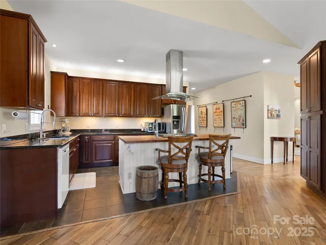 a kitchen with stainless steel appliances kitchen island granite countertop wooden floors a stove a microwave a sink and a refrigerator