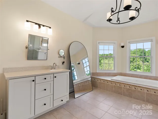 a bathroom with a double vanity sink a two mirror a window and a bathtub