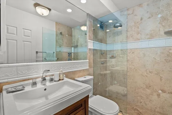 a bathroom with a sink vanity granite toilet and shower