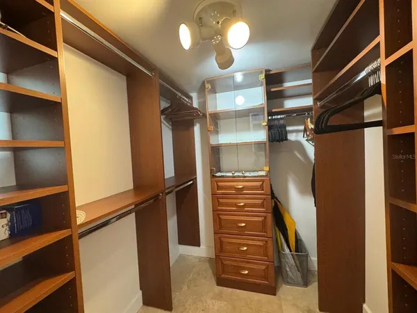 a view of walk in closet with clothes and shoes