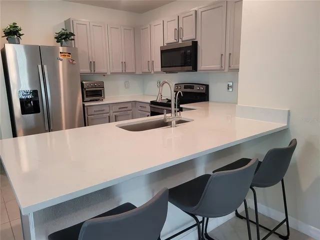 a kitchen with stainless steel appliances a microwave a sink a stove and white cabinets