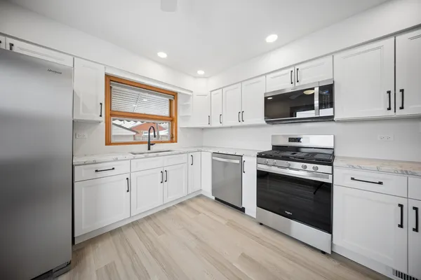 a kitchen with white cabinets stainless steel appliances and sink