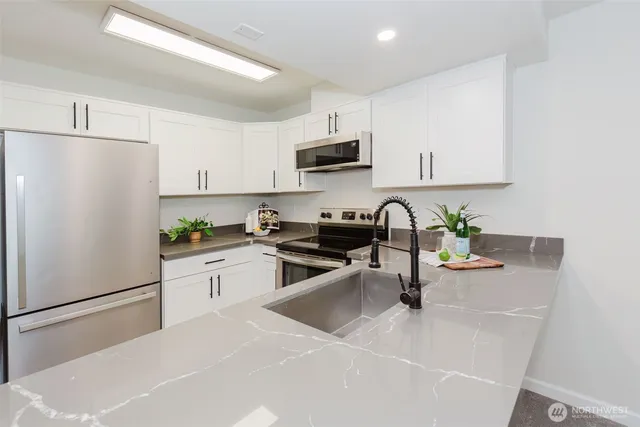 a kitchen with stainless steel appliances a refrigerator sink and white cabinets