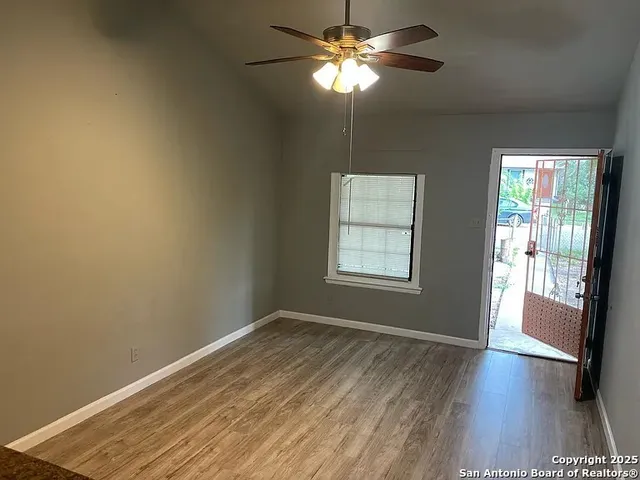 a view of empty room with wooden floor and fan