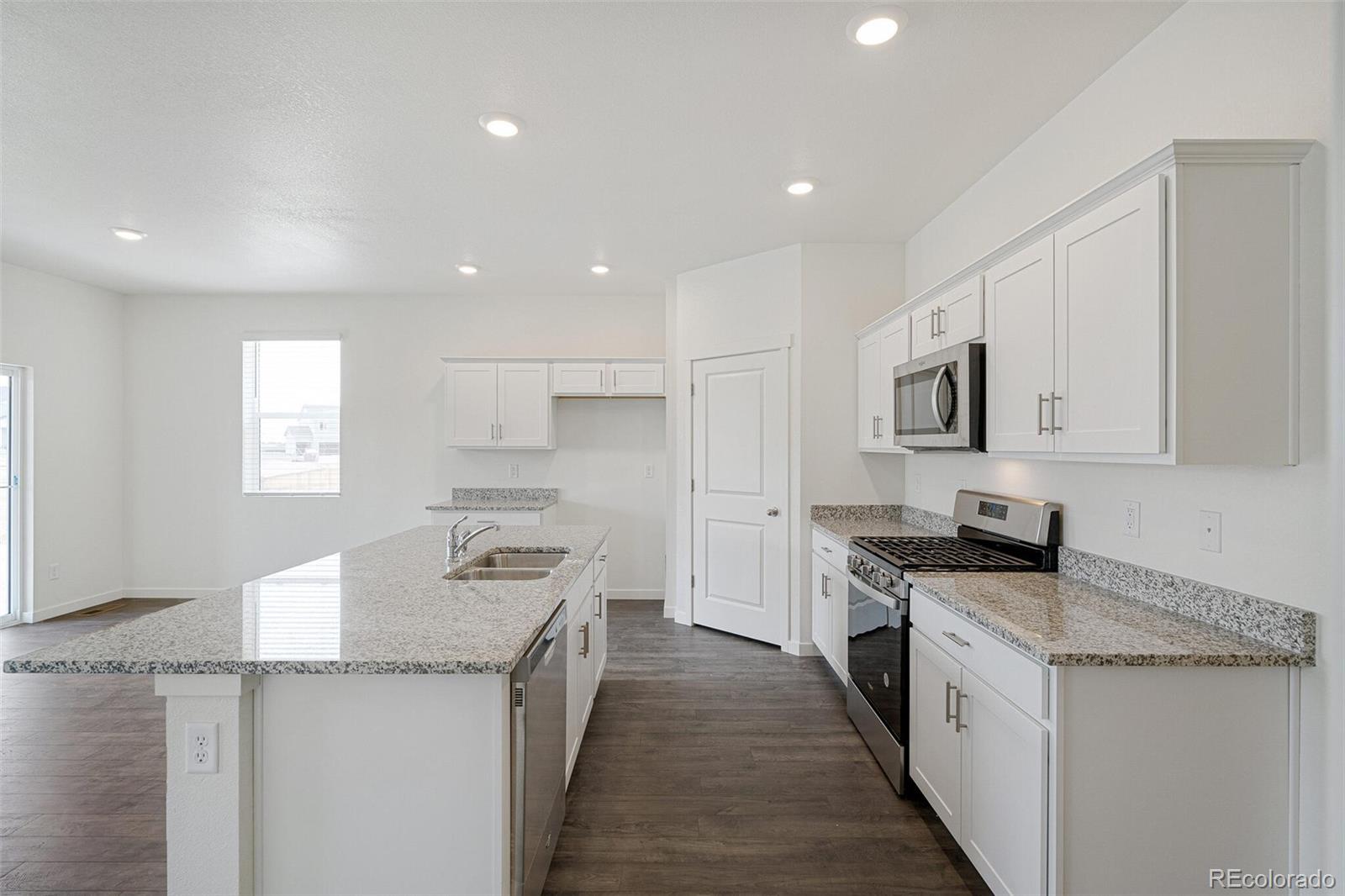 522 Twilight Court Fort Lupton, CO 80621 - Photo 12 of 29 a kitchen with granite countertop a sink stove and cabinets
