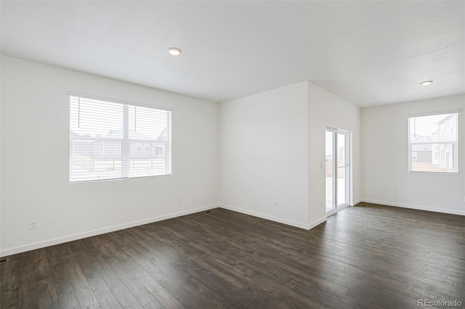 522 Twilight Court Fort Lupton, CO 80621 - Photo 7 of 29 an empty room with wooden floor and windows