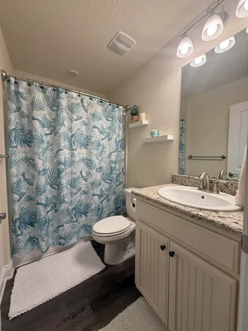 a bathroom with a granite countertop sink toilet and a mirror