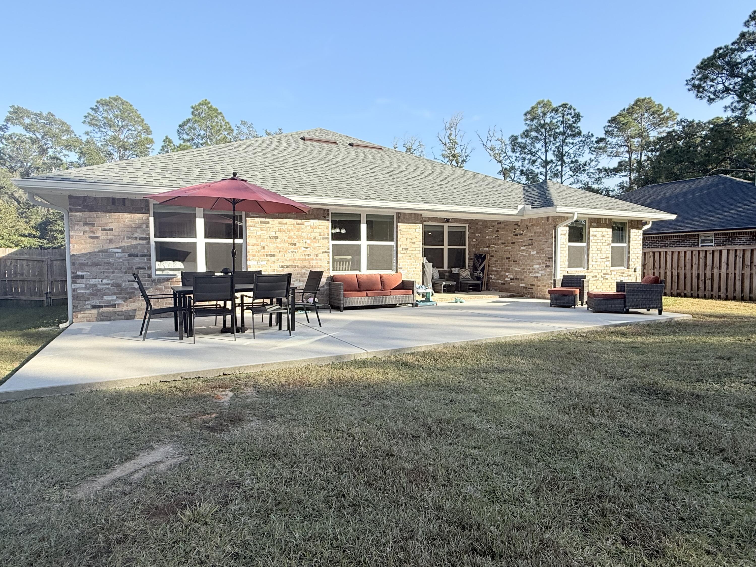 3315 Doyle Hawkins Road Navarre, FL 32566 - Photo 29 of 36 a patio with sofas fire pit table and chairs