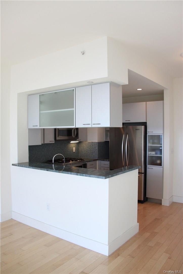 175 Huguenot Street, Unit 1405 New Rochelle, NY 10801 - Photo 4 of 20 a kitchen with stainless steel appliances a sink a stove a refrigerator and cabinets