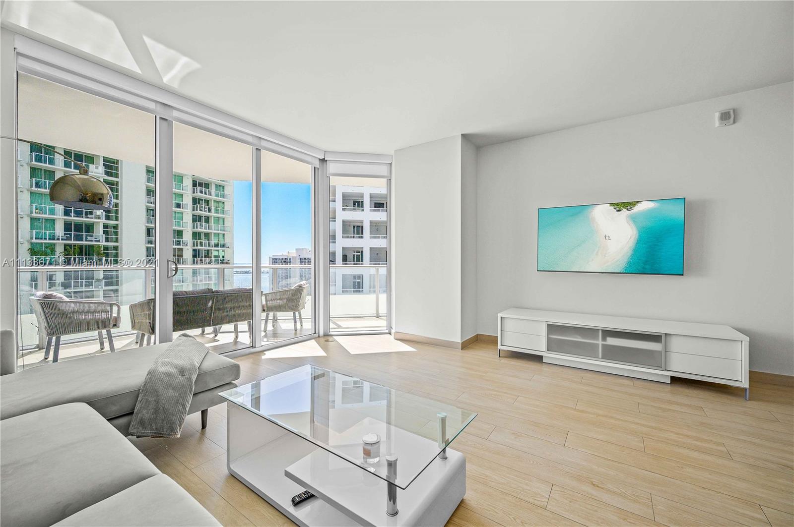 1300 Brickell Bay Drive, Unit 1603 Miami, FL 33131 - Photo 9 of 32 a living room with furniture a flat screen tv and a large window