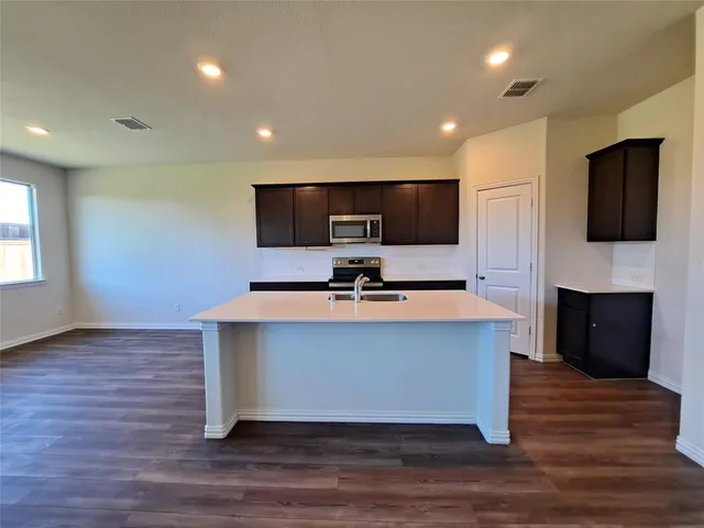 a view of kitchen with kitchen island a sink wooden floor and a fireplace