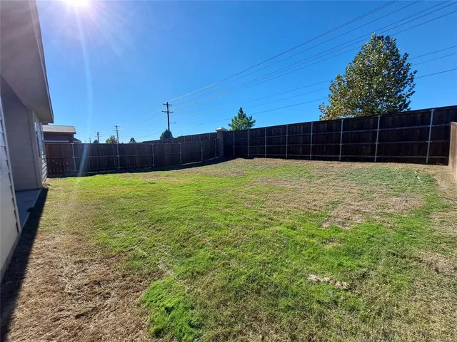 a view of a yard with wooden fence