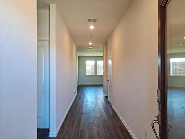 a view of a hallway with wooden floor and a living room