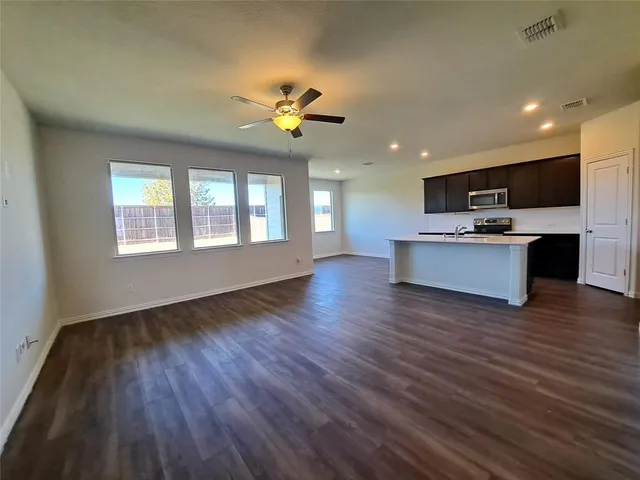 a view of an empty room with a kitchen and wooden floor