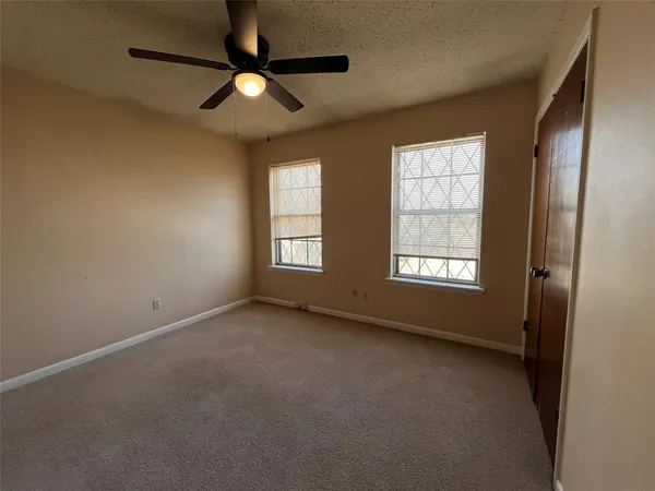 an empty room with windows and fan