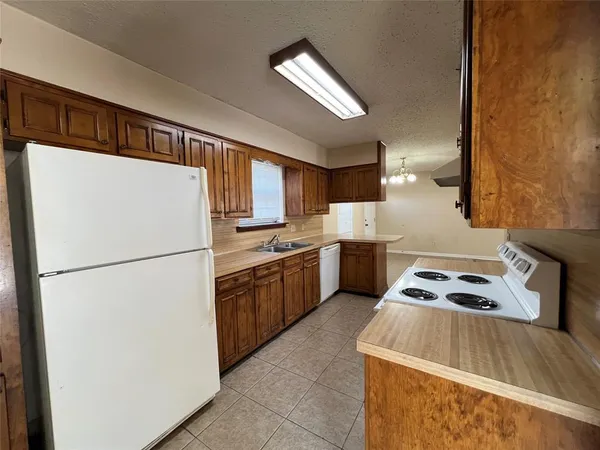 a kitchen with a refrigerator a stove top oven a sink and cabinets