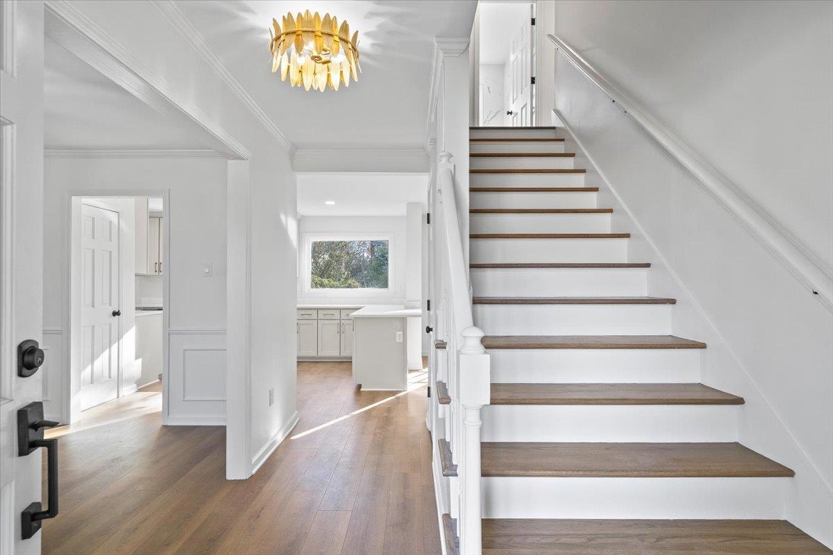 1676 Miller Farms Road Germantown, TN 38138 - Photo 5 of 37 Entryway featuring wood-finish flooring, a contemporary gold-tone flush mount light fixture, and a staircase with white risers and wood-finish treads
