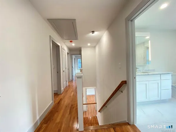 a view of a hallway with wooden floor and staircase