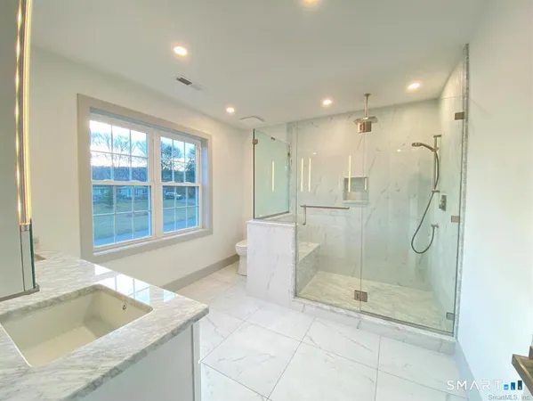 a bathroom with a granite countertop sink a toilet and shower