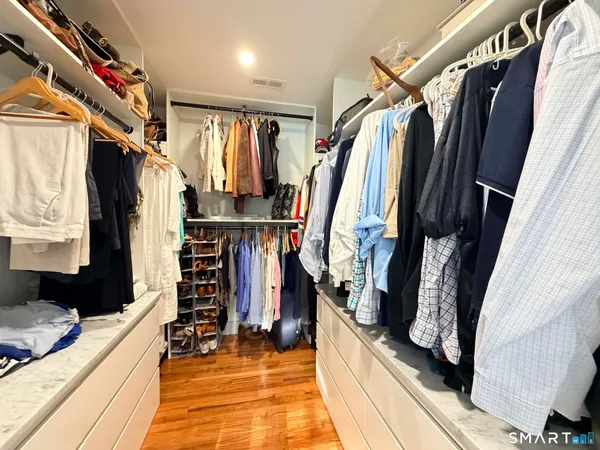 a view of walk in closet with clothes and shoes