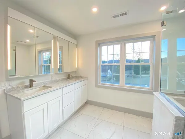a bathroom with a granite countertop sink and mirror with large window