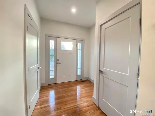 an empty room with wooden floor and a hallway