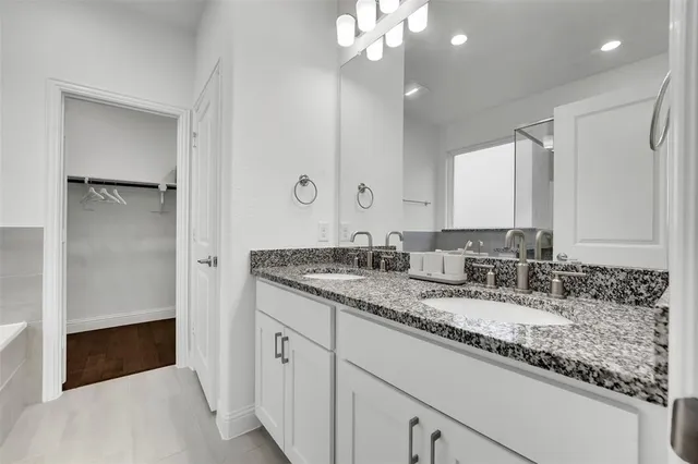 a bathroom with a granite countertop double vanity sink a mirror and shower