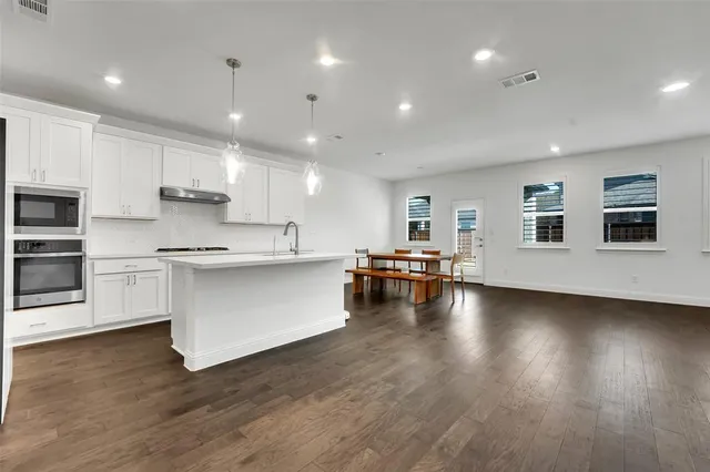 a kitchen with stainless steel appliances granite countertop a stove a sink and a microwave