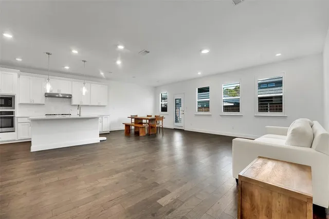 a living room with furniture and kitchen view with wooden floor
