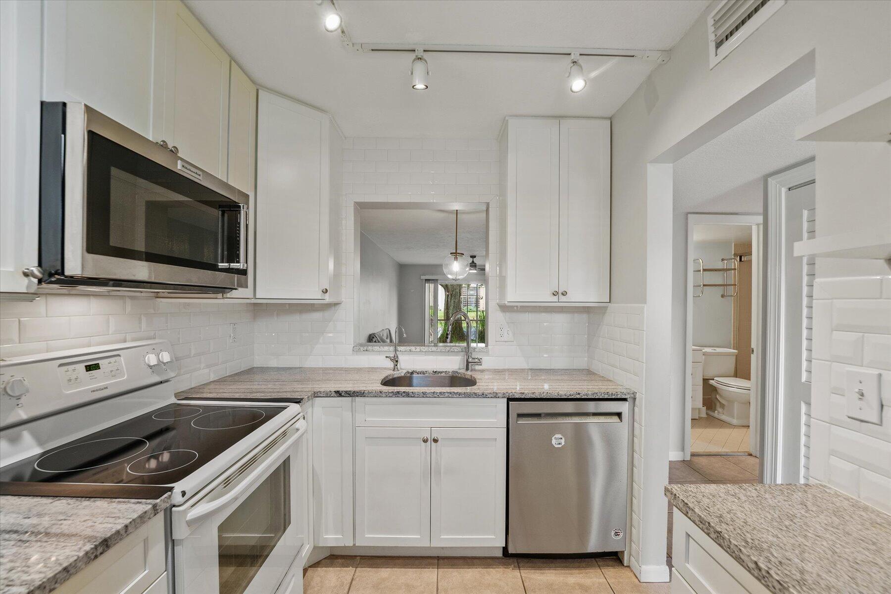 3151 Southeast Aster Lane, Unit 1302 Stuart, FL 34994 - Photo 12 of 23 a kitchen with a sink stove and microwave