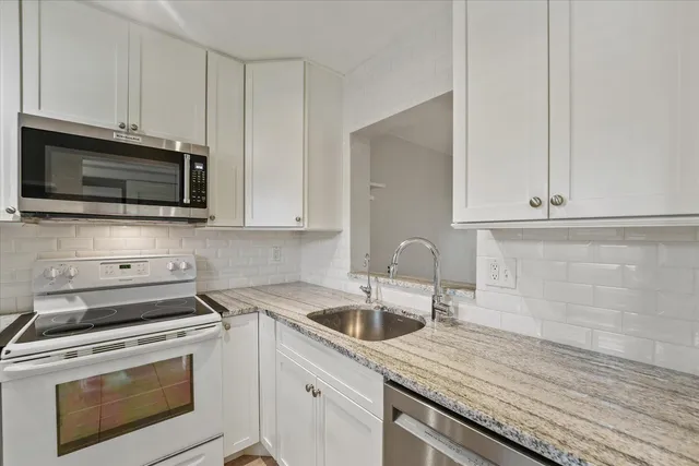 a kitchen with granite countertop white cabinets sink and stainless steel appliances