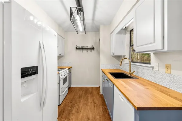 a kitchen that has a sink a refrigerator and a stove top oven