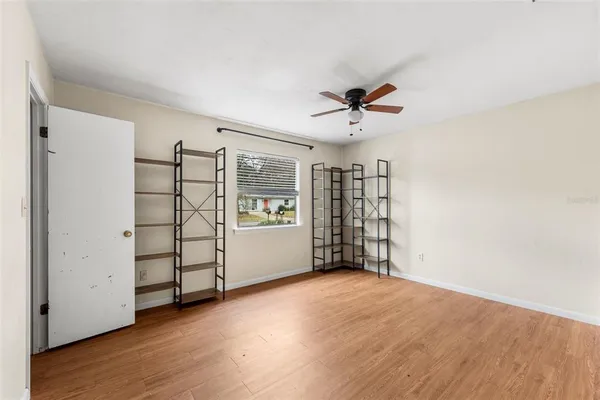 a view of an empty room with a window and wooden floor