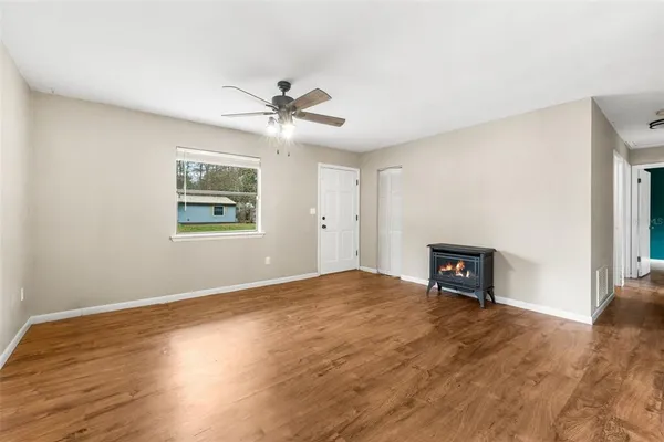 a view of empty room with wooden floor and fan
