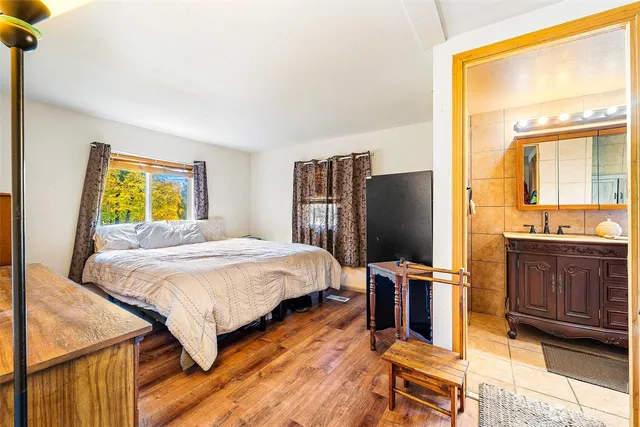 a bedroom with a bed dresser and a flat tv screen next to a window