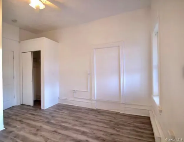 a view of an empty room with window and wooden floor