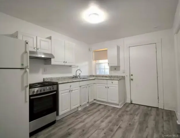 a kitchen with granite countertop white cabinets and white appliances