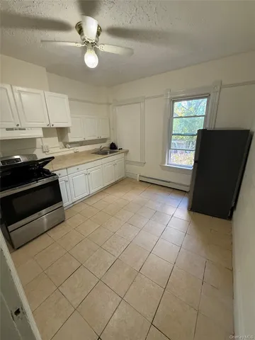 a kitchen with a sink a stove cabinets and a window