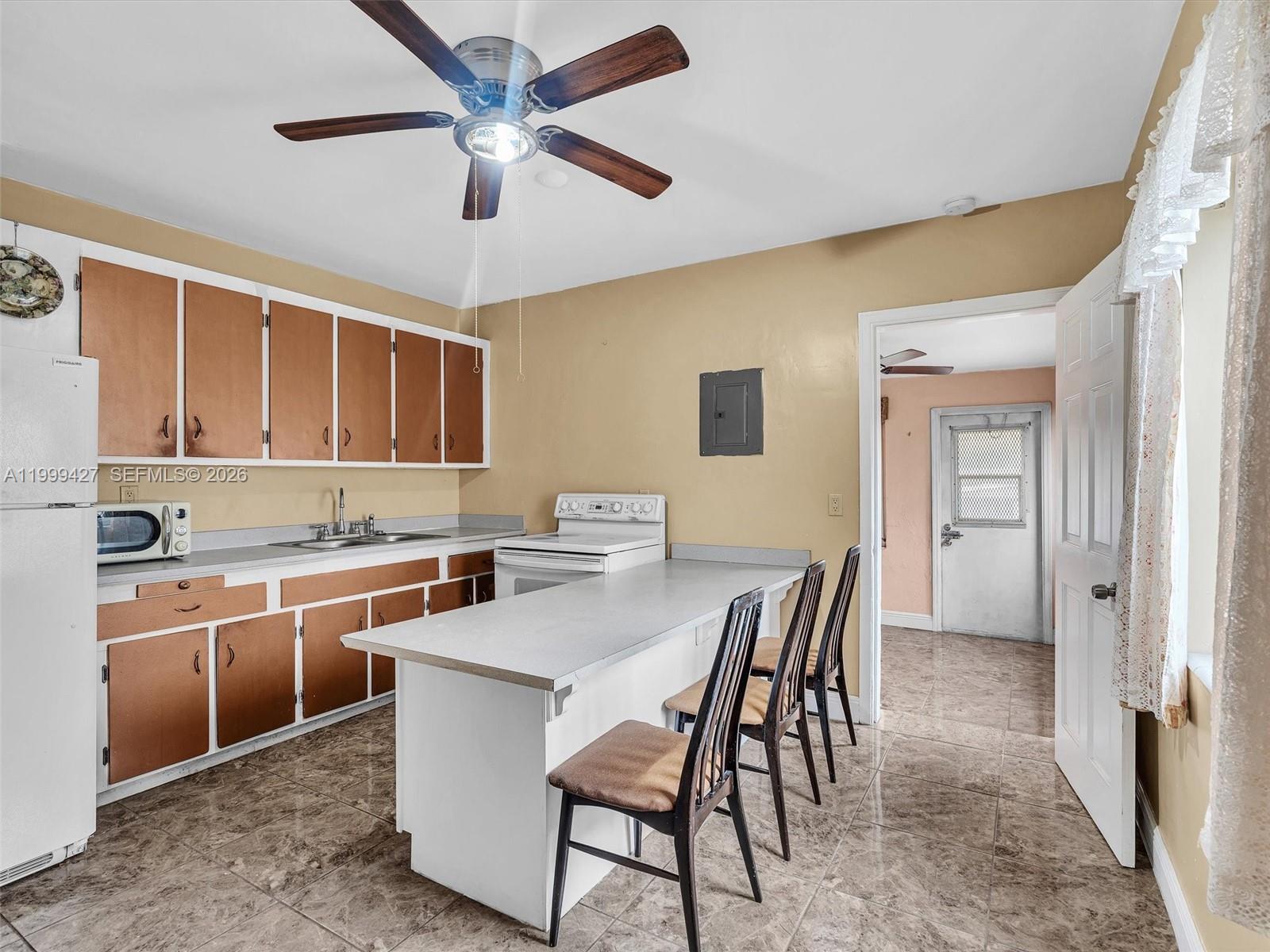 10 Southwest 72nd Avenue Miami, FL 33144 - Photo 8 of 35 a kitchen with a table chairs refrigerator and cabinets