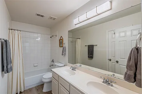 a bathroom with a double vanity sink toilet mirror and shower