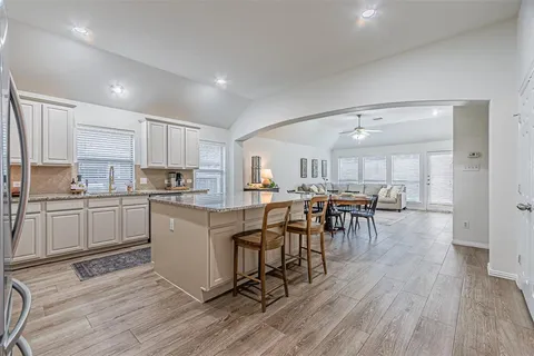 a kitchen with a table chairs wooden floors and white stainless steel appliances