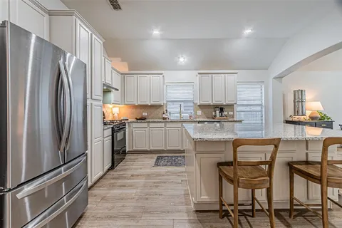 a kitchen with kitchen island white cabinets and stainless steel appliances