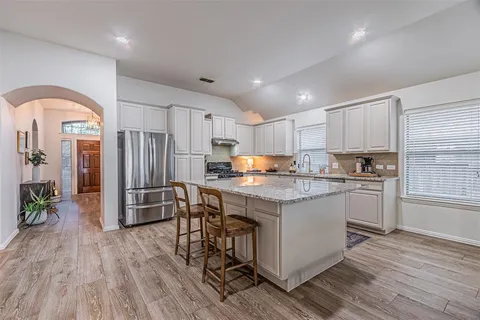 a kitchen with stainless steel appliances granite countertop a refrigerator and a stove top oven