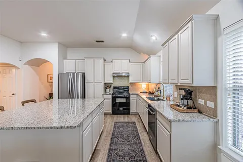 a kitchen with granite countertop a sink stainless steel appliances and cabinets